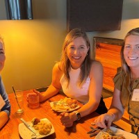 Alumnae eating together in a booth at Long Road Distillers